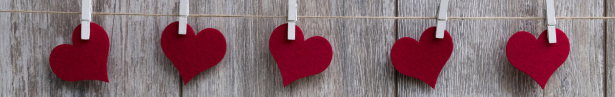 red felt hearts pegged to a washing line white wood behind